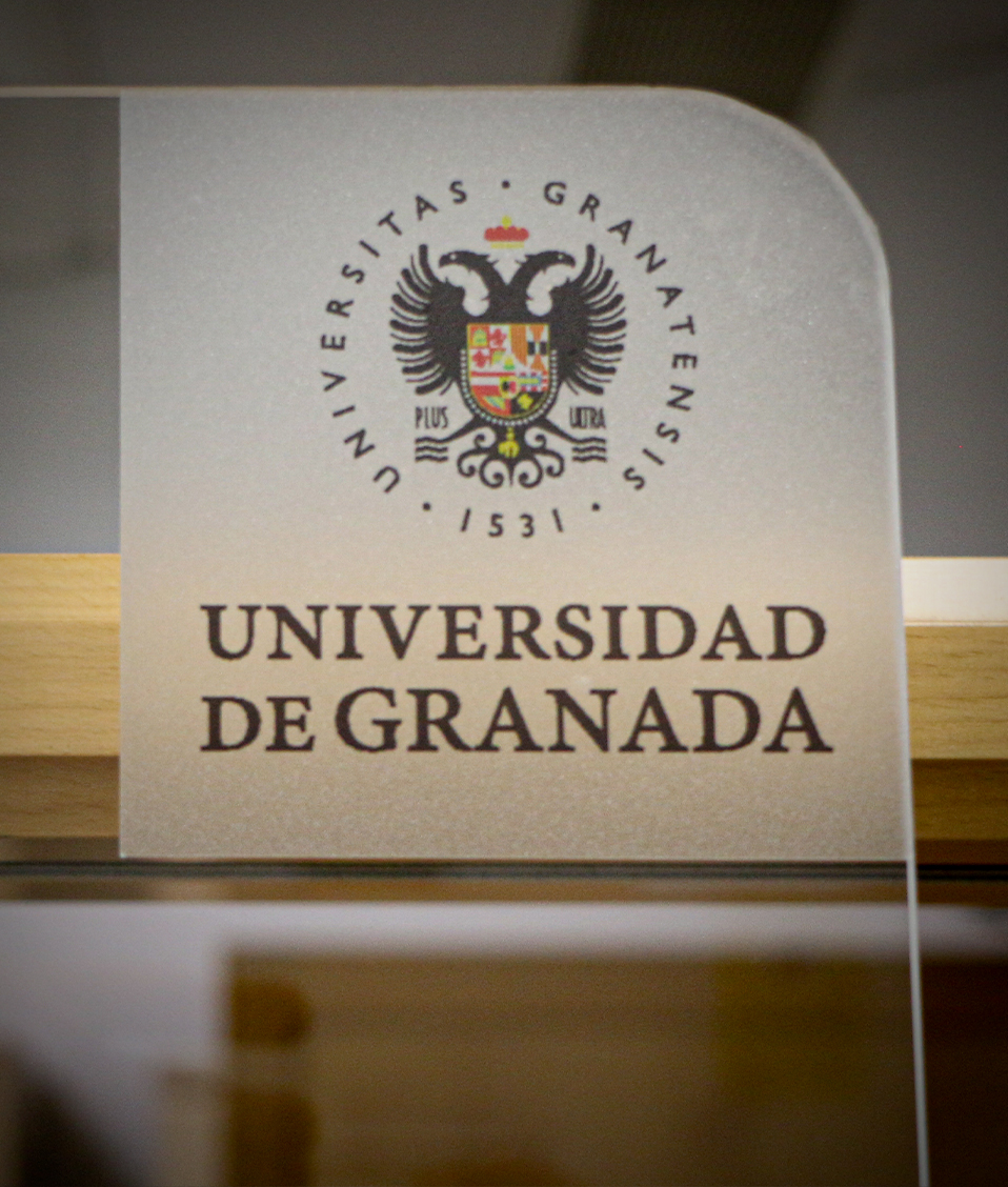 Pegatina con el logotipo de la Universidad de Granada colocada en el cristal de la conserjería del Edificio San Jerónimo