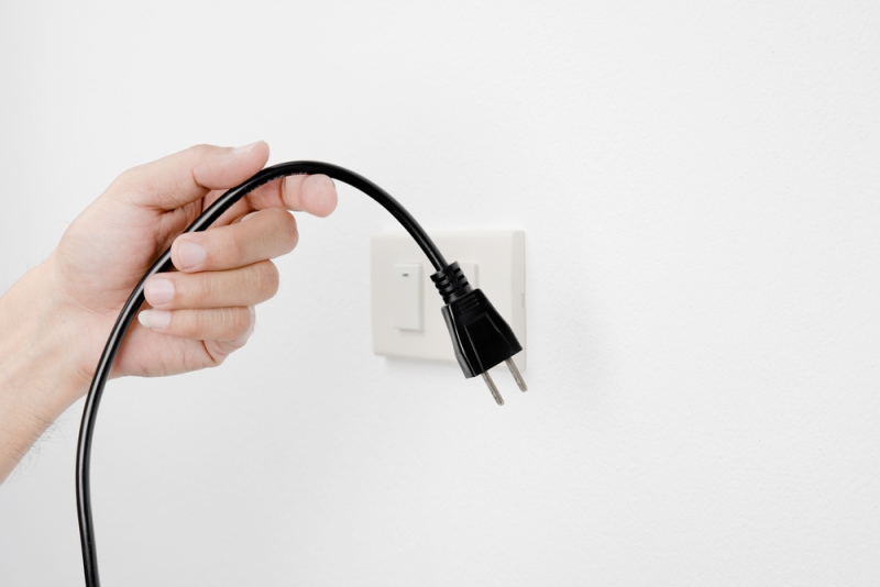 cable con enchufe en una mano con enchufe detrás